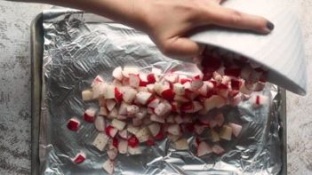 pouring raw diced radishes onto a baking tray