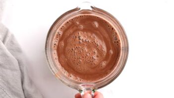 A glass measuring cup with chocolate ice cream mixture inside.