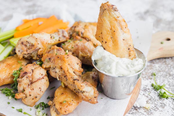 dipping a chicken wing into some blue cheese dressing