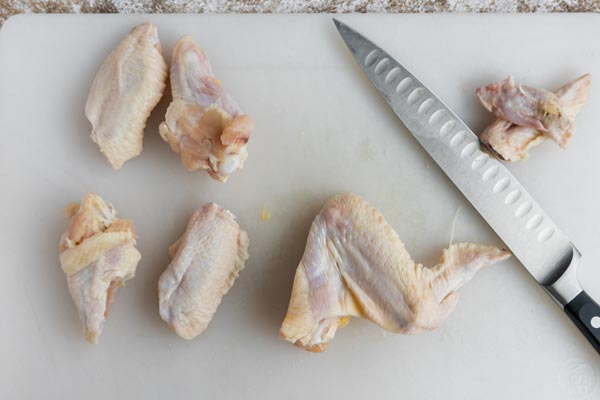 cutting whole chicken wings into drumettes and wingettes with a knife