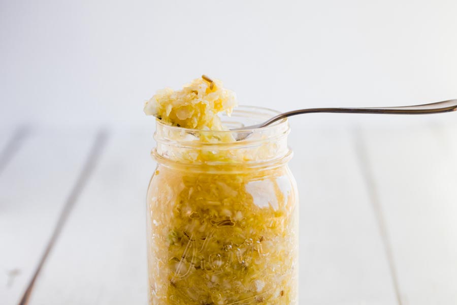a fork balancing on top a mason jar holding fresh sauerkraut