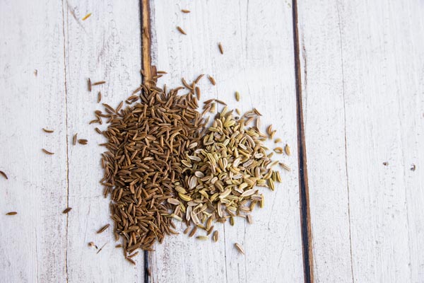 fennel seeds and coriander seeds on a white wooden table