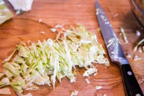 thinly sliced pieces of cabbage next to a knife