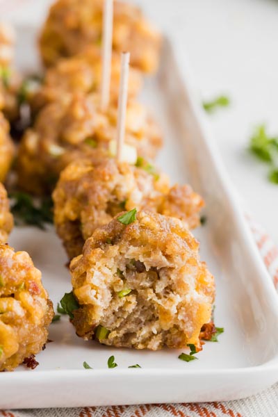 a bite out of a sausage ball on a plate with a row of more balls behind it