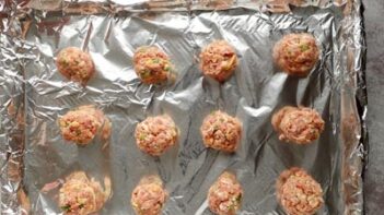 meatballs lined up on a foil lined baking tray