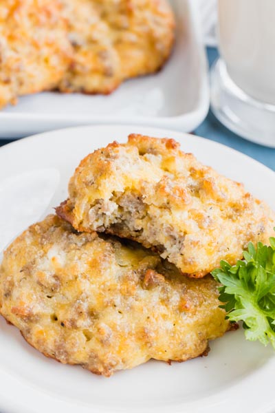 A sausage filled biscuit on a plate with a bite out of it.