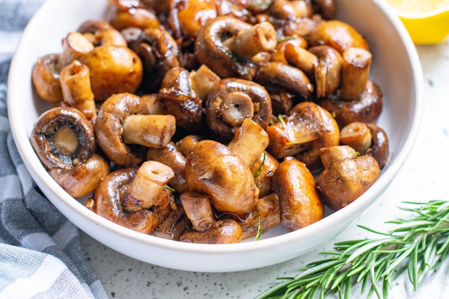 a mushroom side dish on the table with rosemary