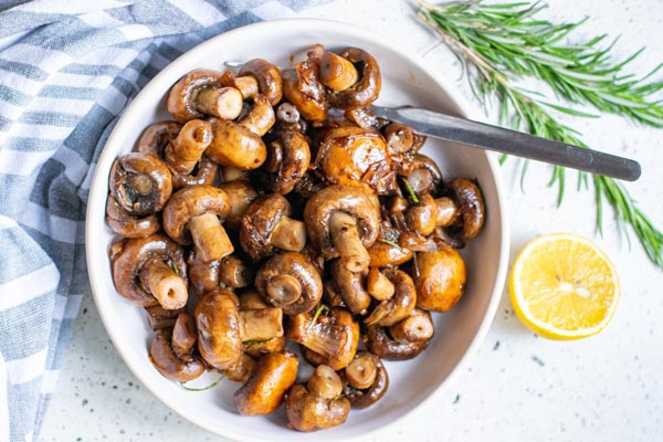 buttery mushrooms and onions in a bowl with lemon and rosemary near