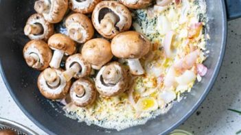 sauteed onions and whole mushrooms in a skillet