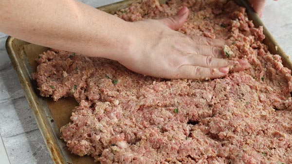 pressing the meatloaf onto a sheet pan
