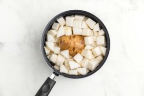 A saucepan with diced turnips and a potato in the middle.