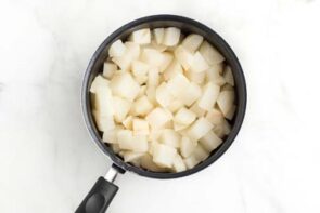 A saucepan filled with cooked diced turnips.