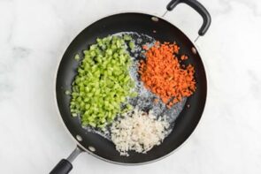 A skillet with chopped celery, carrot and onion.