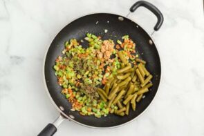 A skillet filled with sautéed vegetables and green beans.