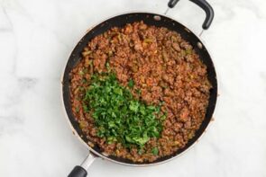 A skillet filled with cooked ground beef and parsley on top.