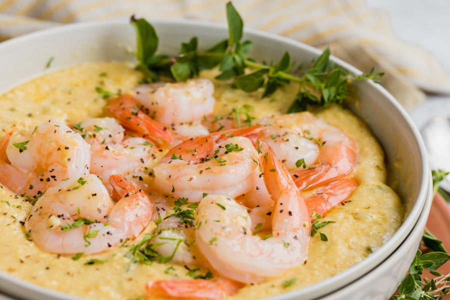 a pile of shrimp on a bowl of keto grits in a beige bowl