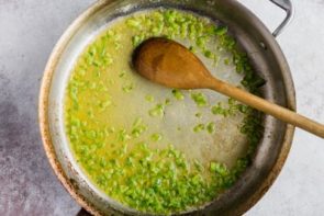 a wooden spoon cooking diced jalapeno with butter