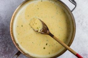 a skillet with keto grits cooking in it and a wooden spoon