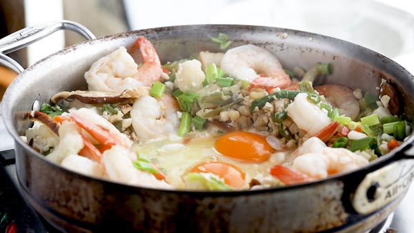 fresh eggs in the center of a skillet with fried rice around