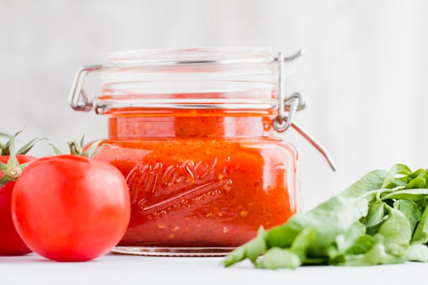 keto tomato sauce in a mason jar next to parsley and a whole tomato