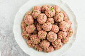 a plate stacked with uncooked meatballs