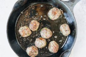 meatballs cooking in a cast iron skillet