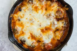 melted cheese over pasta sauce in a cast iron skillet