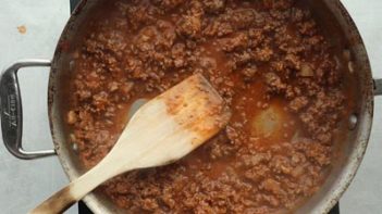 thickened sloppy joes sauce in a skillet with a wooden spoon