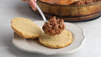 ladelling sloppy joe mix onto a keto hamburger bun