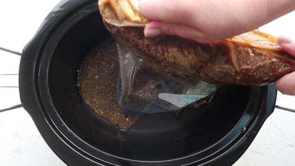 pouring low carb marinated pork tenderloin into a slow cooker liner