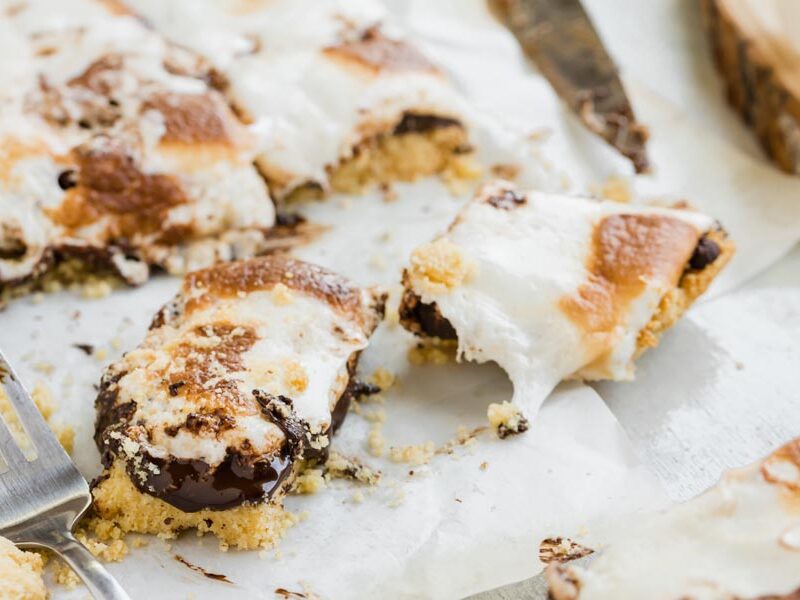 messy, gooey marshmallow bars cut on a parchment paper with a fork nearby