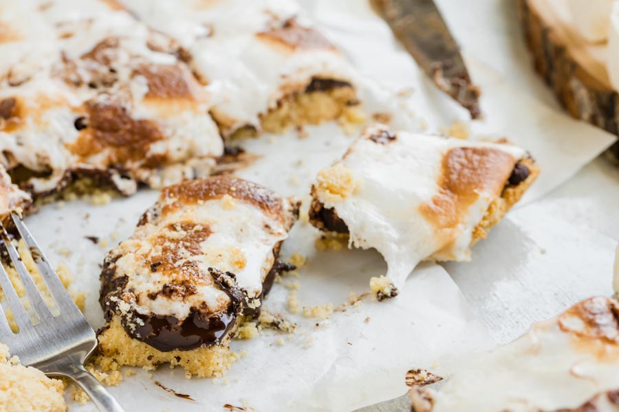 messy, gooey marshmallow bars cut on a parchment paper with a fork nearby