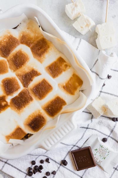 toasted marshmallows covered a baking dish with chocolate and unroasted marshmallows around