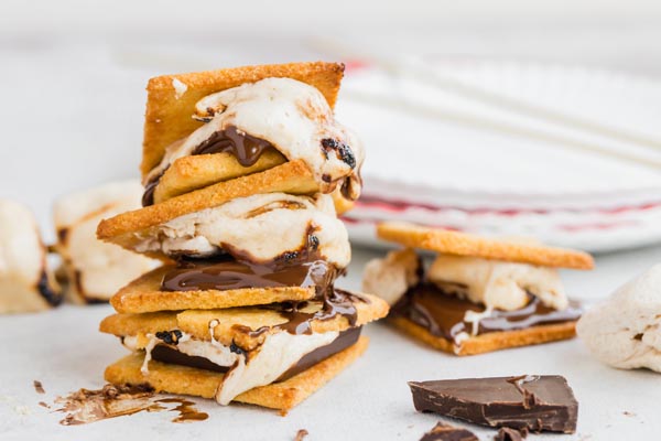 a stack of three smores with a smore and broken chocolate next to it
