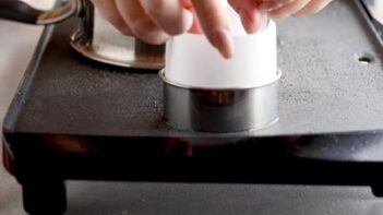 placing a ring of parchment paper inside a biscuit cutter ring place on an electric griddle
