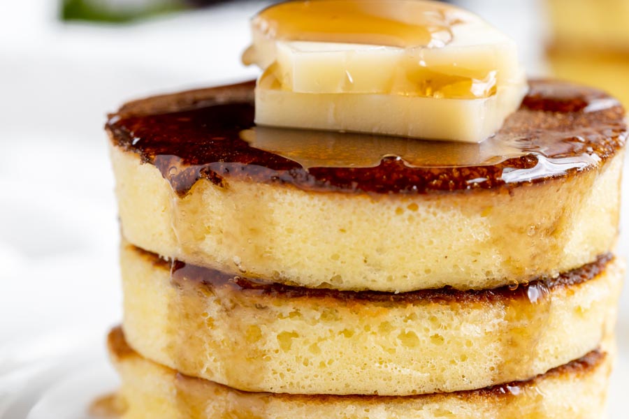 close up of a pancake stack with syrup running down the edges