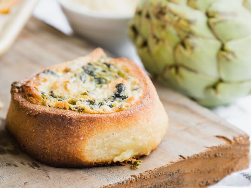Close up of a golden spinach artichoke pinwheel bun with golden brown pastry crust.