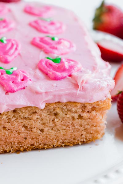 a strawberry cake topped with a pink strawberry frosting decorated with strawberries