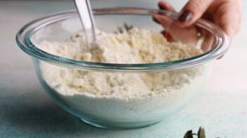 stirring dry ingredients in a clear bowl with a wire whisk