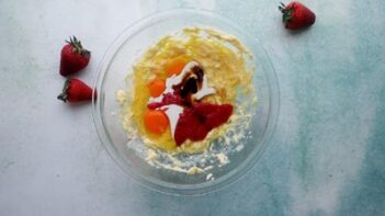 cake ingredients in a bowl with fresh strawberries around