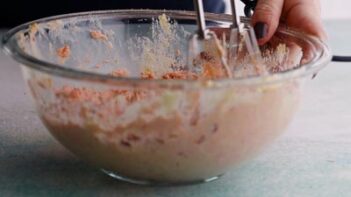 mixing pink cake batter in a bowl with an electric mixer