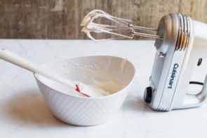 blender sitting next to a white bowl after whipping cream