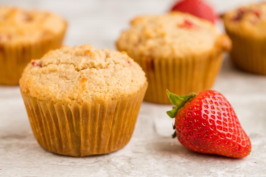 straight on view of muffins with strawberries slices in them and a red strawberry