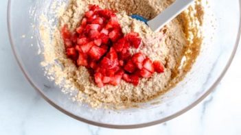 sliced strawberries sitting on top muffin batter