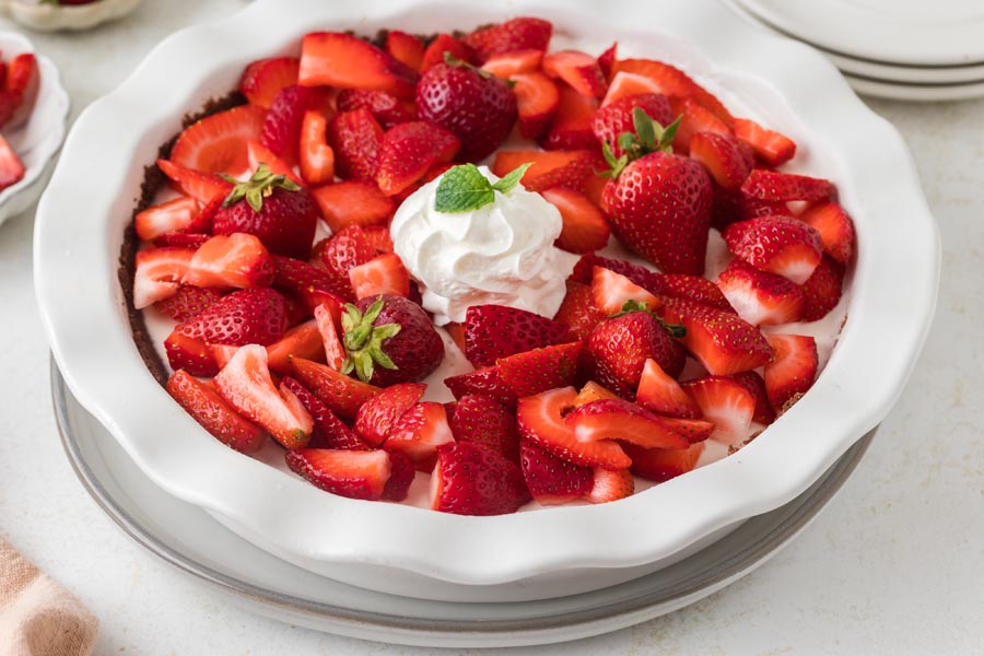 Overhead view of a full strawberry cream pie topped with sliced and whole strawberries and a dollop of whipped cream.