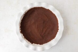 Chocolate crust mixture pressed evenly into a white pie dish.