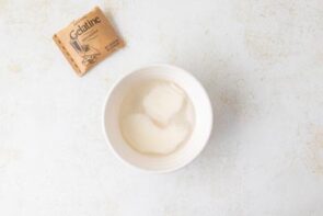 A bowl with water and unflavored gelatin packet being bloomed.
