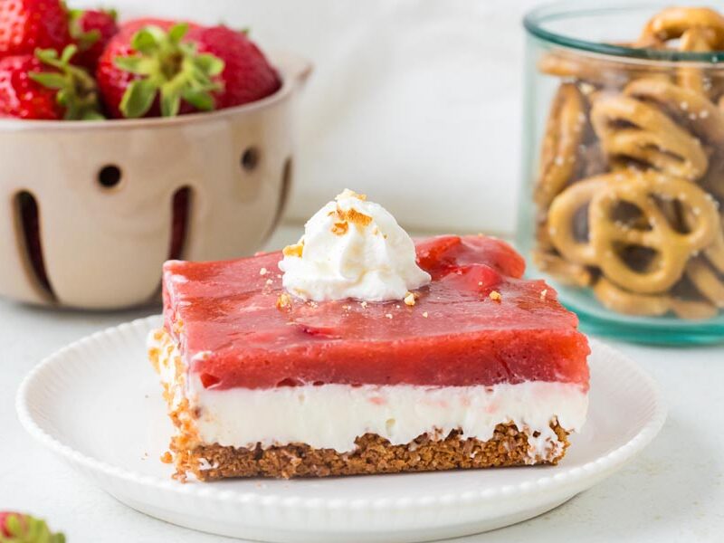 Slice of keto strawberry pretzel salad with whipped cream, strawberries and pretzels.
