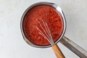 Strawberry mixture being whisked in a saucepan until smooth.