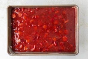 The final strawberry gelatin mixture spread evenly over the cream layer in a rectangular pan.